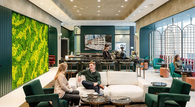 Centre Lounge with green decor, showcasing two individuals networking on a sofa against a city backdrop