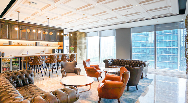 Contemporary lounge showcasing leather couches, a barista bar, and a stunning view of the cityscape